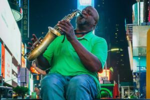 Nesta imagem, um músico, vestido com uma camisa verde e calças jeans, concentra - se em tocar o sassofone no vibrante ambiente de um local provavelmente Times Square, com cartazes iluminados ao fundo. A arte e a emoção transmitidas pela sua performance são palpáveis. É nesse contexto de diversidade e conexão global que &ldquo;Sobre BaoLiba – Conectando Influenciadores e Marcas Portuguesas ao Mundo 🌍&rdquo; surge, ajudando a levar a cultura e o talento portugueses para o cenário internacional, assim como a música nesse momento chega aos ouvidos das pessoas ao seu redor.